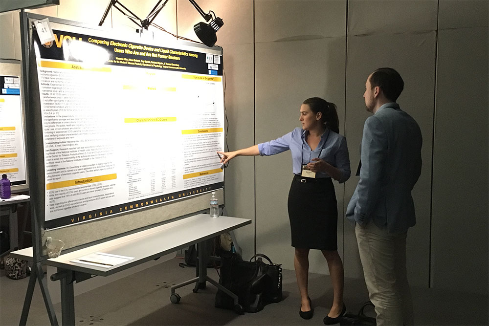 CSTP student explains a research poster to another person